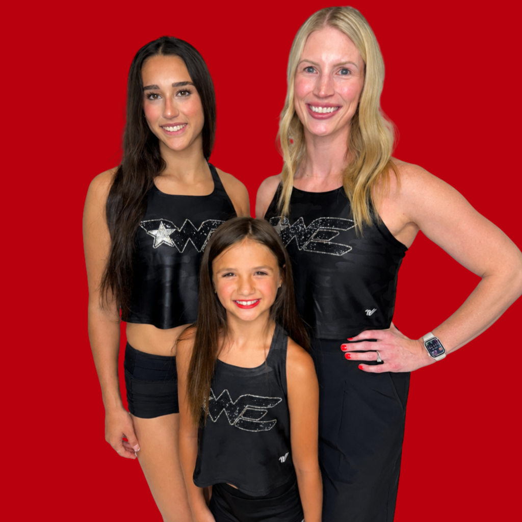 Three women posing together in matching black athletic outfits with a red background, all smiling at the camera.